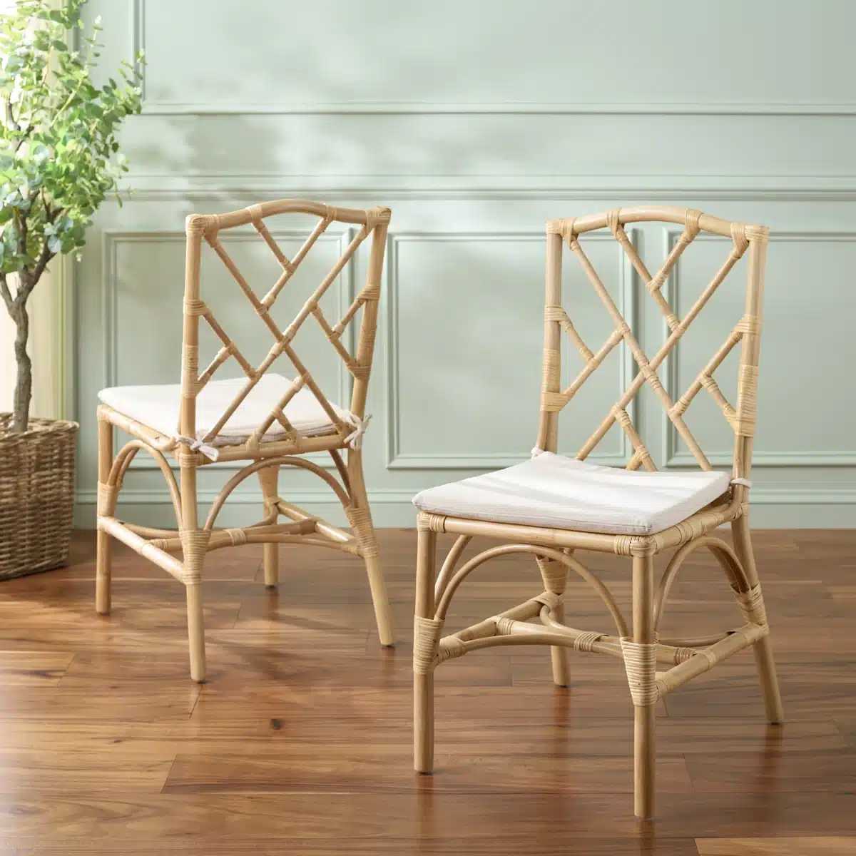 Natural woven rattan dining chairs with removable white cushions in a coastal dining room style.