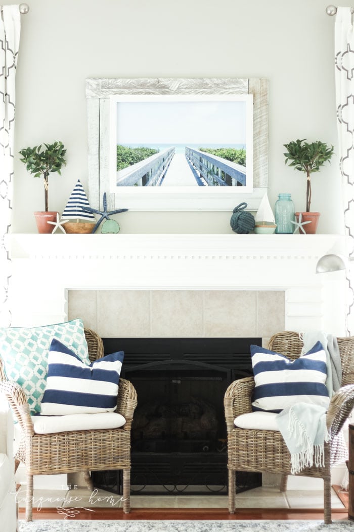 A coastal summer mantel decor ideas. Add a little nautical charm to your living space with these simple coastal summer mantel decor ideas. Featuring DIY beach canvas art, blue & white starfish, textured sailor's knot and cheerfully striped sail boats, this mantel looks great for the seasonally inspired.
