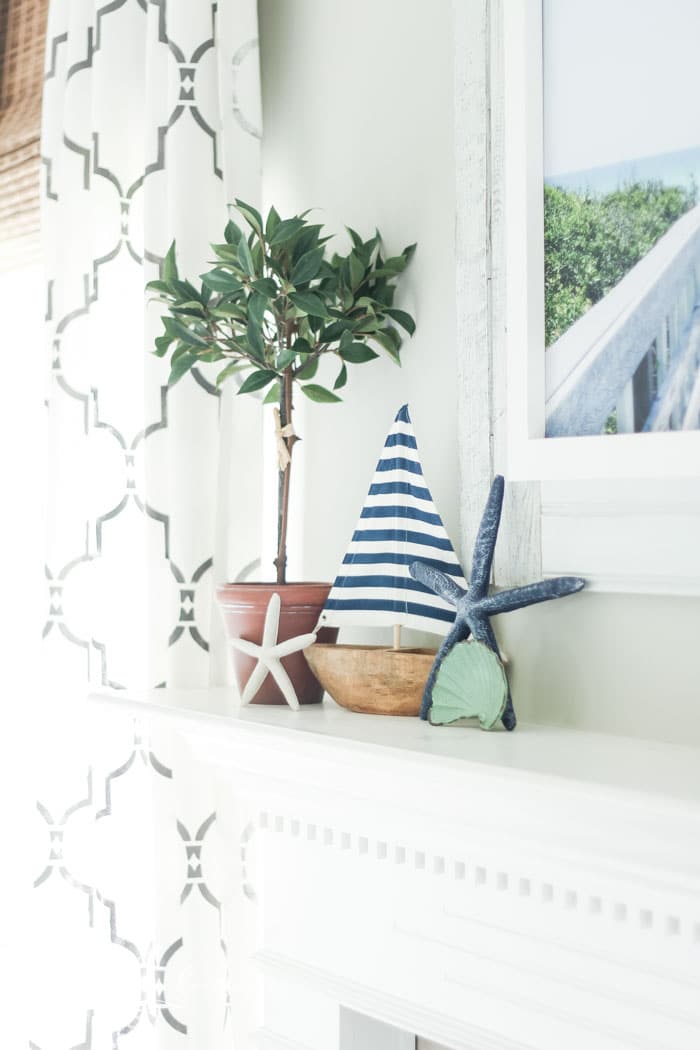 Add a little nautical charm to your living space with these simple coastal summer mantel decor ideas. Featuring DIY beach canvas art, blue & white starfish, textured sailor's knot and cheerfully striped sail boats, this mantel looks great for the seasonally inspired.