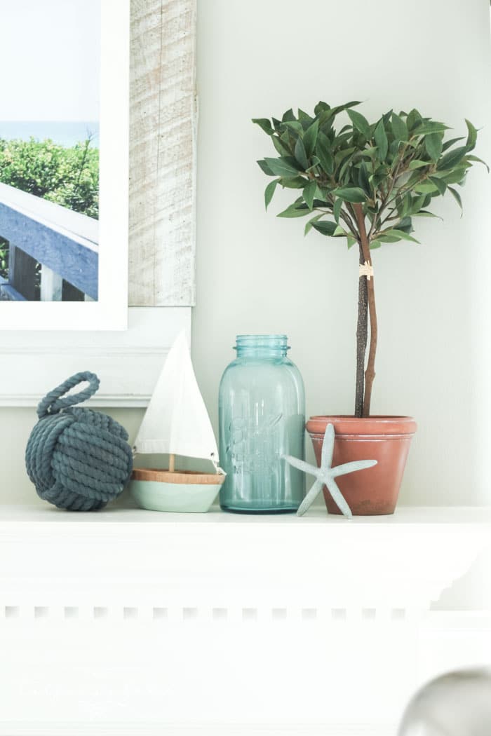 Add a little nautical charm to your living space with these simple coastal summer mantel decor ideas. Featuring DIY beach canvas art, blue & white starfish, textured sailor's knot and cheerfully striped sail boats, this mantel looks great for the seasonally inspired.