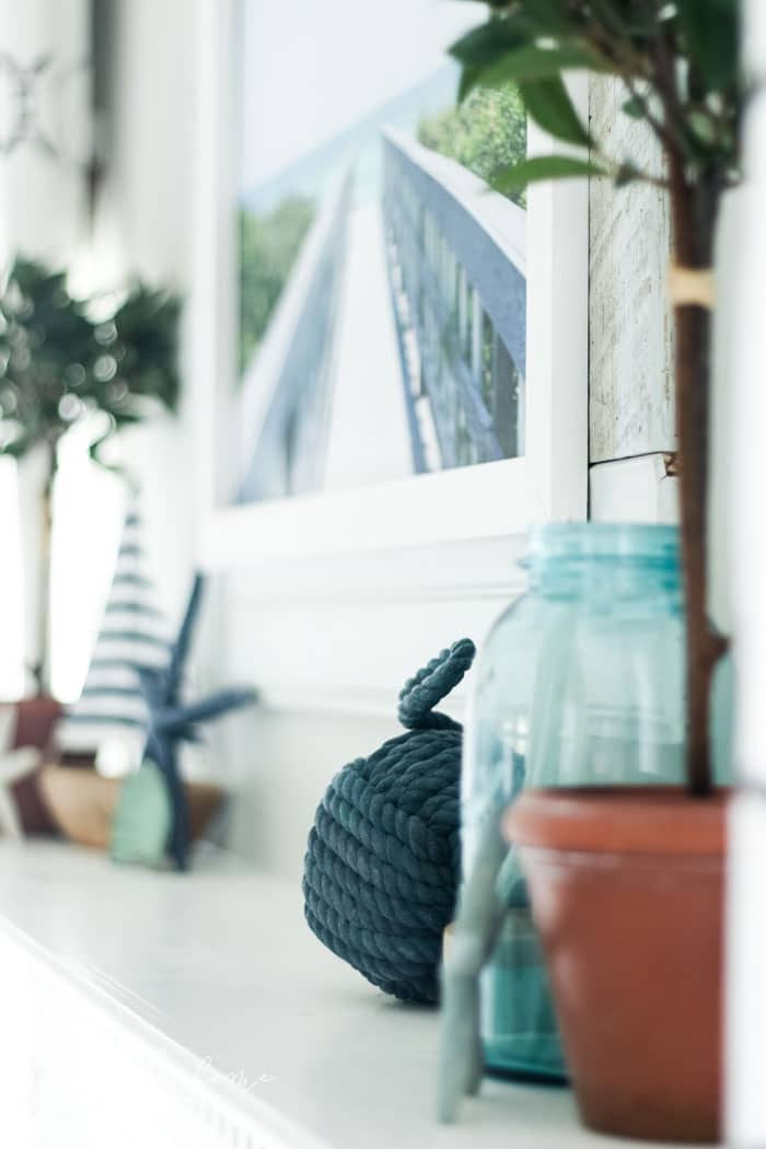 Add a little nautical charm to your living space with these simple coastal summer mantel decor ideas. Featuring DIY beach canvas art, blue & white starfish, textured sailor's knot and cheerfully striped sail boats, this mantel looks great for the seasonally inspired.