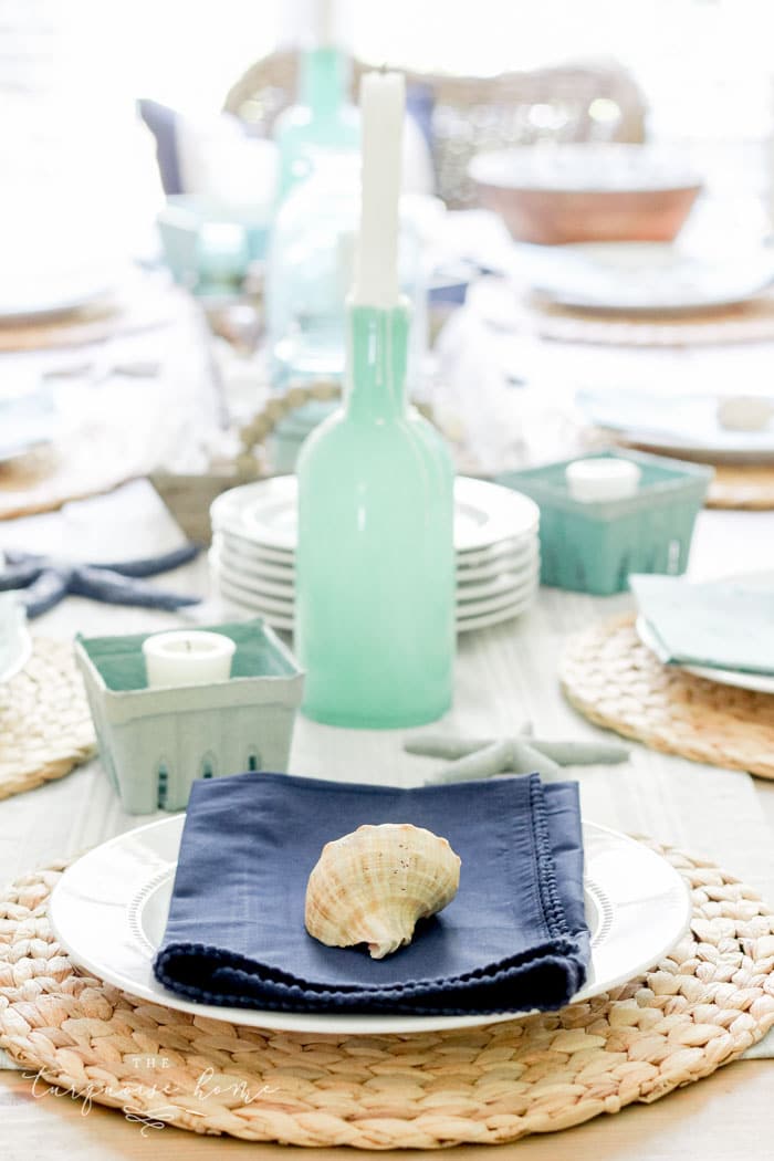 Coastal Decor in the Dining Room with white plate, rattan charger and shell decor.