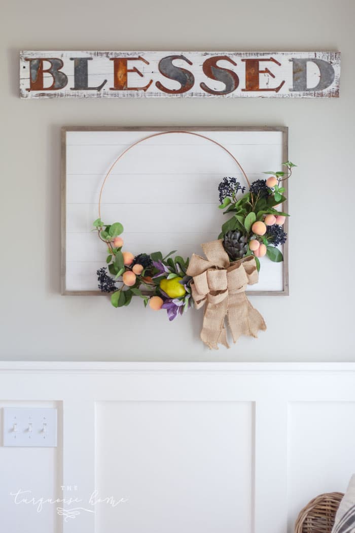 Gorgeous fall wreath with fruit on a "shiplap" framed backdrop.