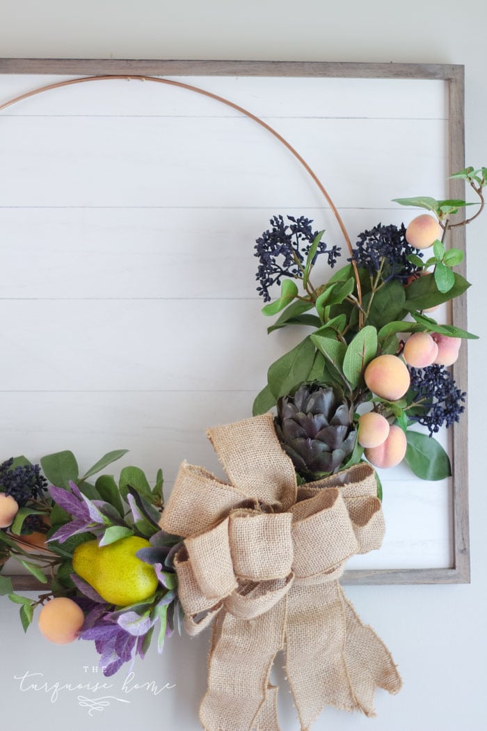 Gorgeous fall wreath with fruit on a "shiplap" framed backdrop.