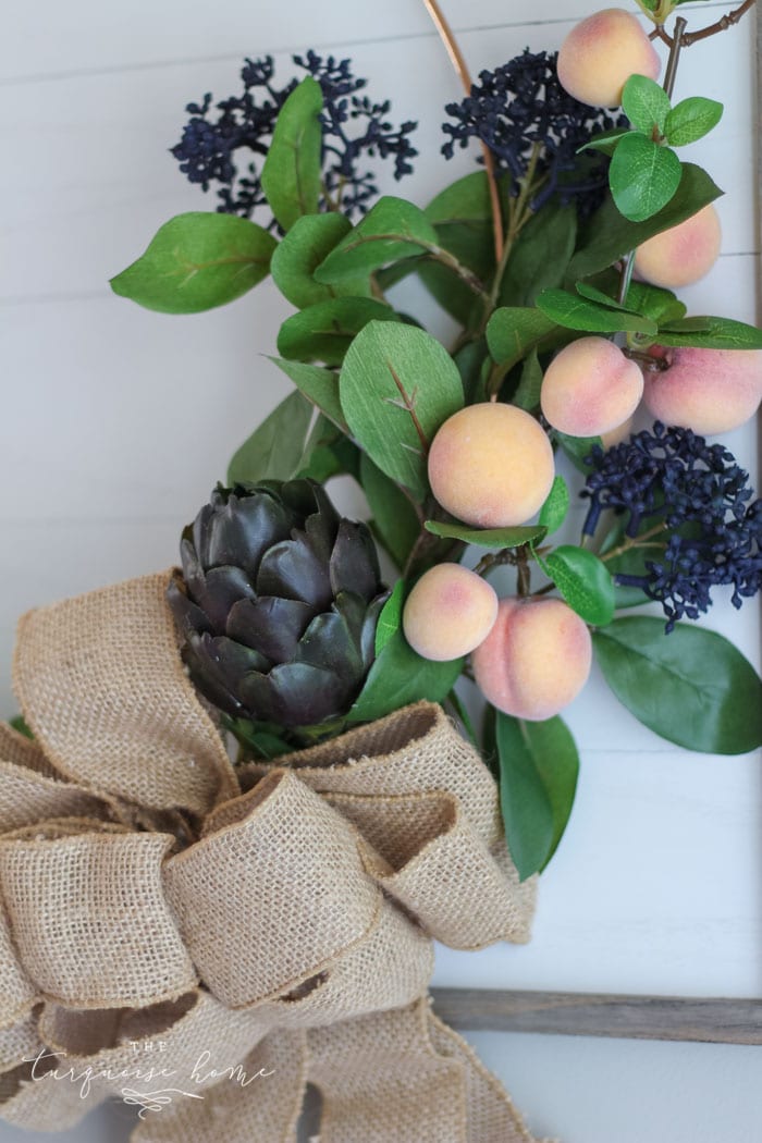 Gorgeous fall wreath with fruit on a "shiplap" framed backdrop.