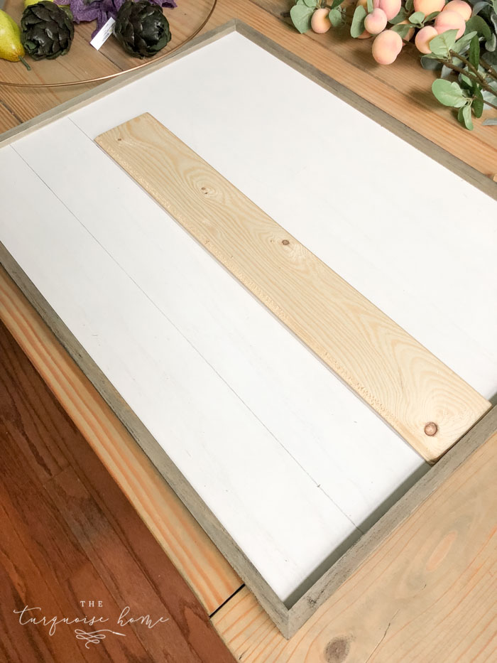 Draw "shiplap" lines on the framed board with a pencil and a scrap piece of wood!