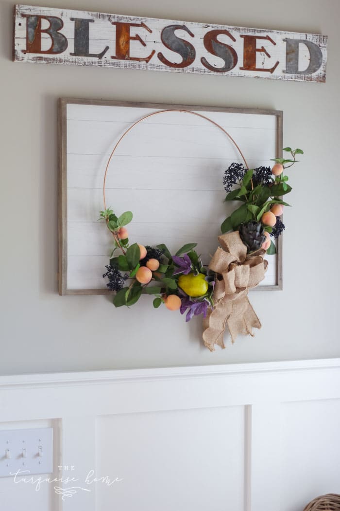 Gorgeous fall wreath with fruit on a "shiplap" framed backdrop.