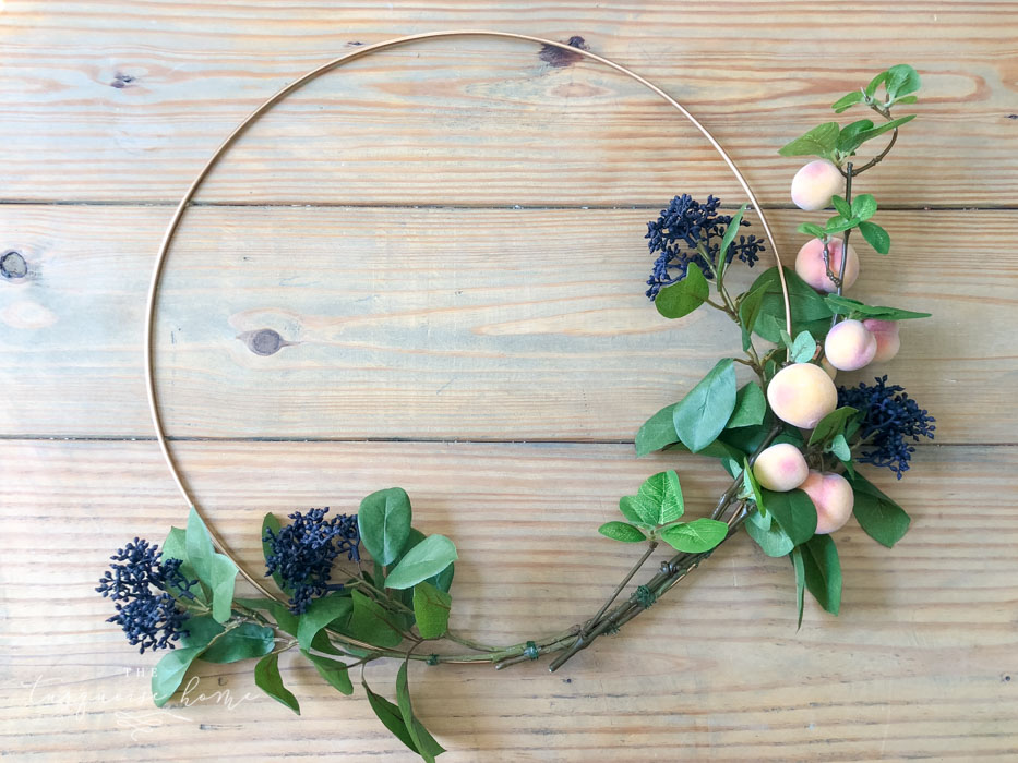 Attach the floral and fruit stems to the wreath hoop.