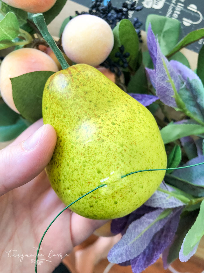 Add faux fruit to the fall wreath.