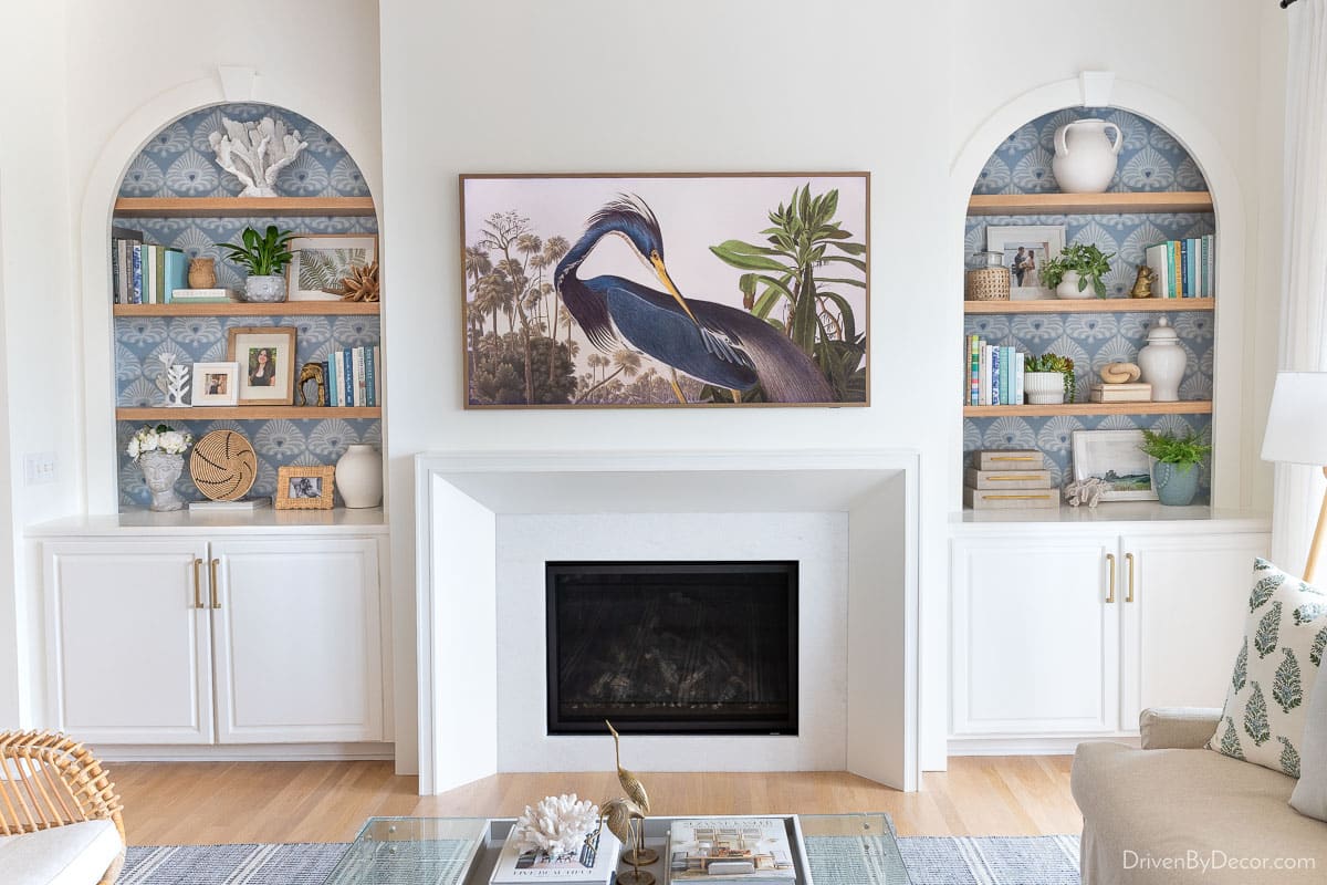 styled bookcases flanking a modern white fireplace with a TV art above it.