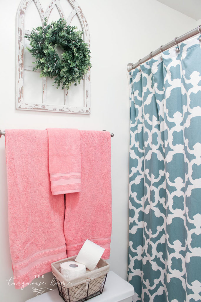 Window arch above the toilet in the girls' bathroom refresh | Use a basket for toilet paper storage and a over-the-toilet cabinet if needed | bathroom makeover | pink towels | antique distressed window frame | eucalyptus wreath