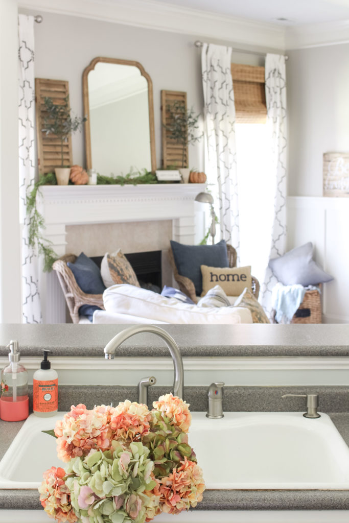 Green and coral pink hydrangeas grace the white sink in a cozy fall kitchen. Lots of fall home decor ideas in this post!