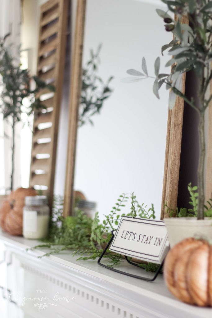 Shutter and olive tree with "let's stay home" sign and a wood grain pumpkin. Fall Mantel Decor #fallmantel #manteldecor #falldecor #homedecor