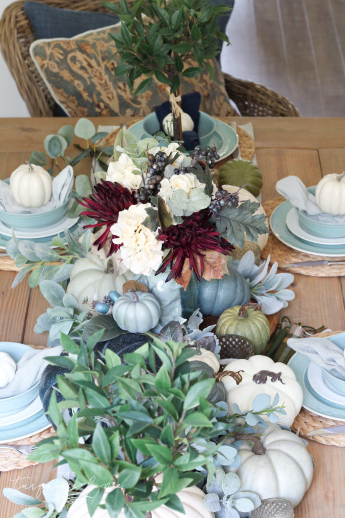 Pumpkins and Greenery Fall Tablescape with bay leaves in a pot and fall floral arrangement. 