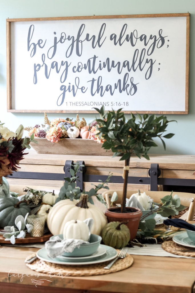 Pumpkins and Greenery Fall Tablescape with bay leaves in a pot and fall floral arrangement. 
