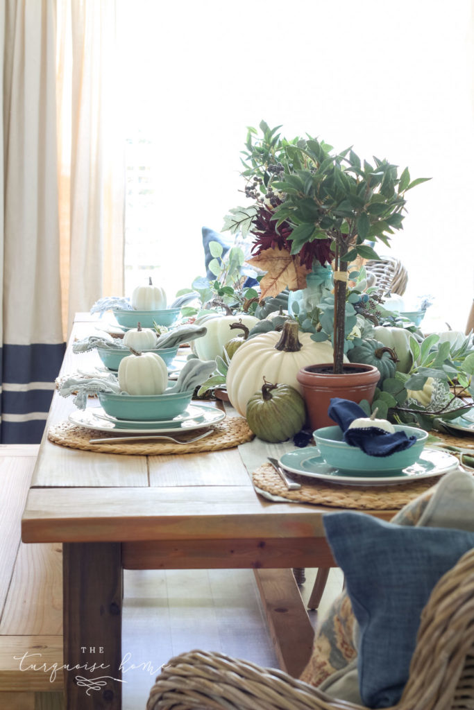 Pumpkins and Greenery Fall Tablescape with bay leaves in a pot and fall floral arrangement. 