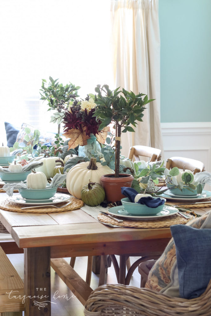 Pumpkins and Greenery Fall Tablescape with bay leaves in a pot and fall floral arrangement. 