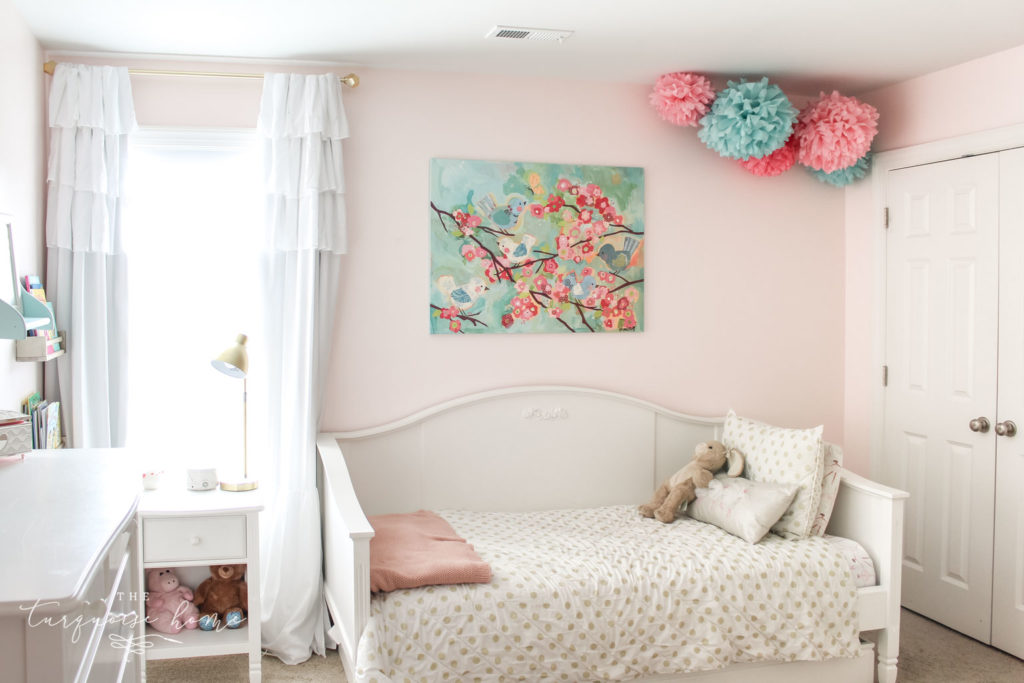 Pink girl's bedroom with art above bed