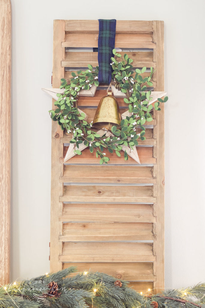 Rustic shutter with wooden star, wreath and Christmas bell decor.