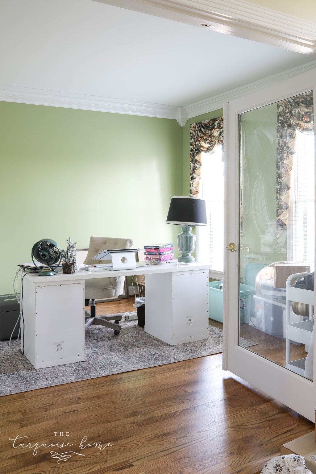 Feminine office with lime green walls and desk in the middle of the room.