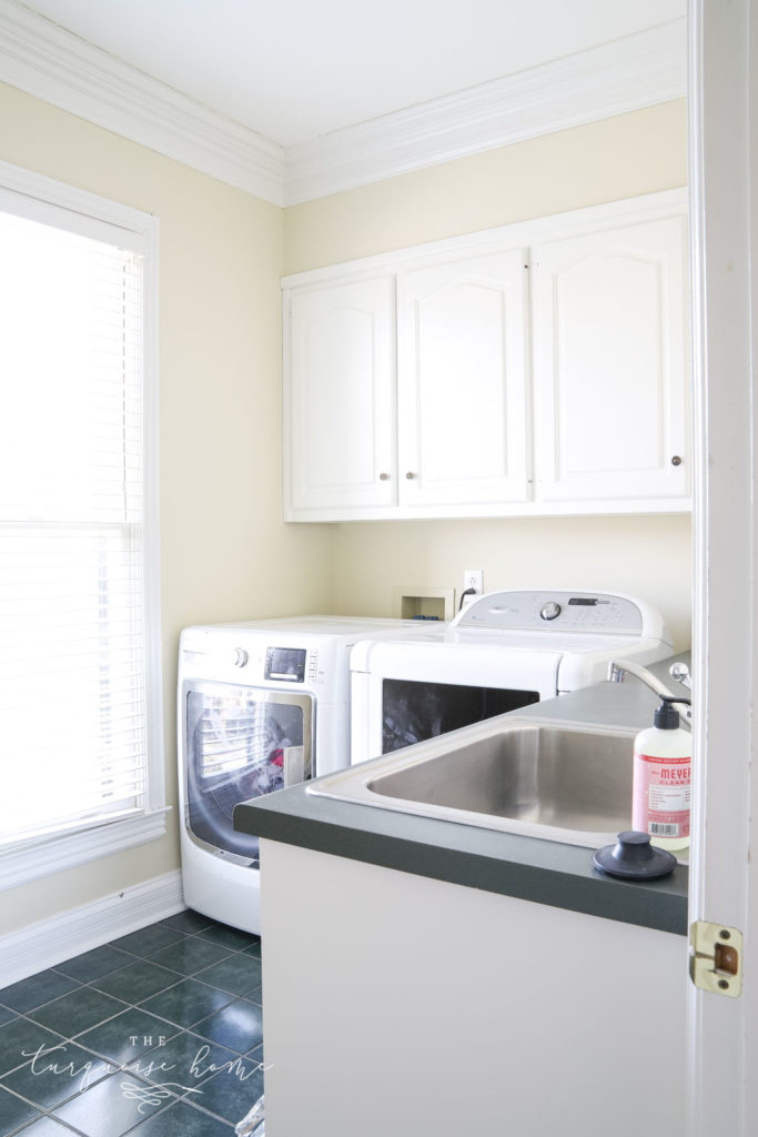 Laundry room with lots of storage, hunter green tiles on the floor and hunter green countertops. 