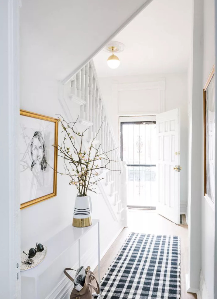 white hallway with narrow white console table and blue checked runner rug