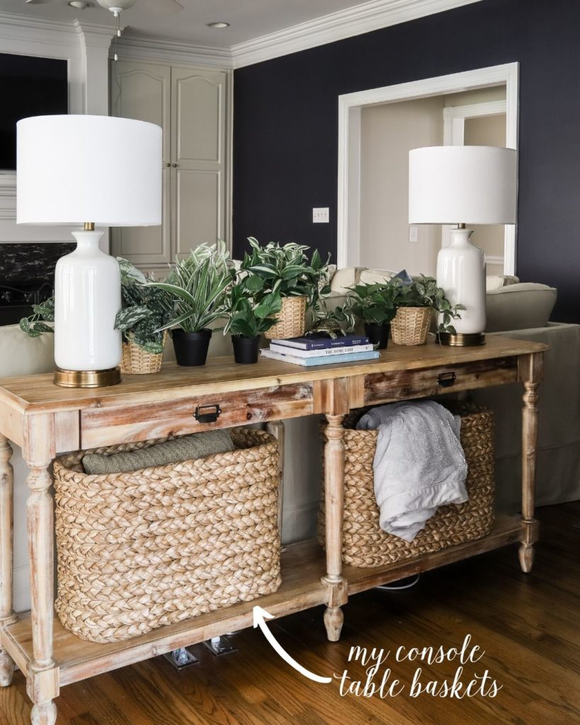 Everett Console Table with console table baskets, white lamps, faux plants and hale navy walls in living room