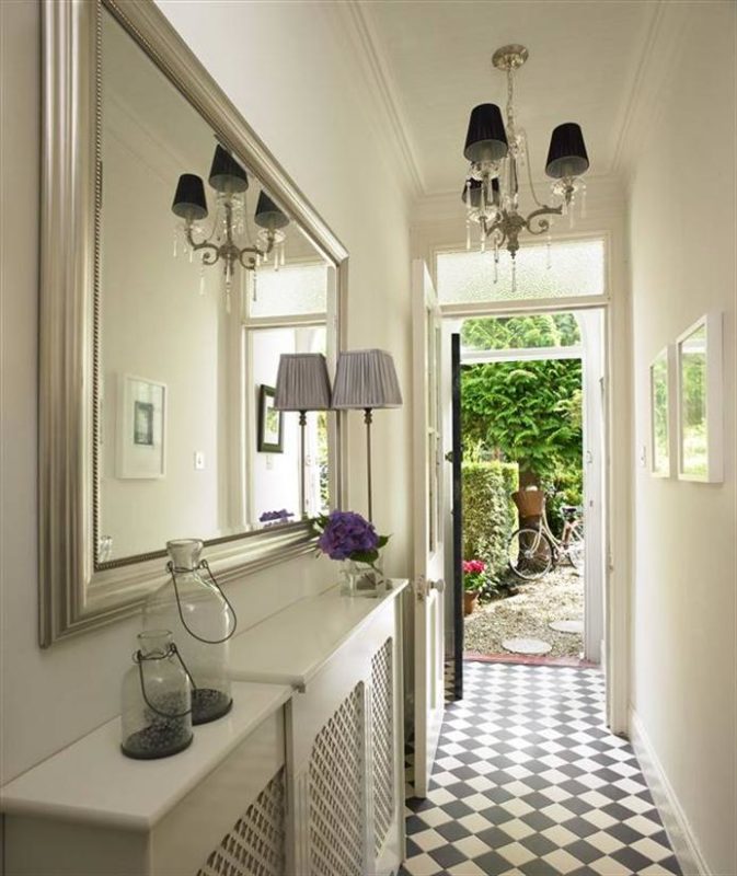 hallway with console table and hanging mirror to reflect the light