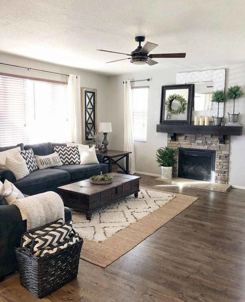 farmhouse style living room with couch in front of a window, a fireplace, and a coffee table