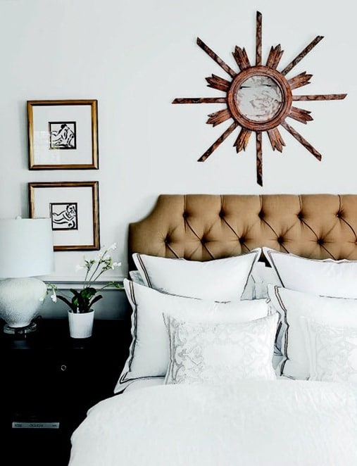 sunburst mirror hanging on the wall above a bed