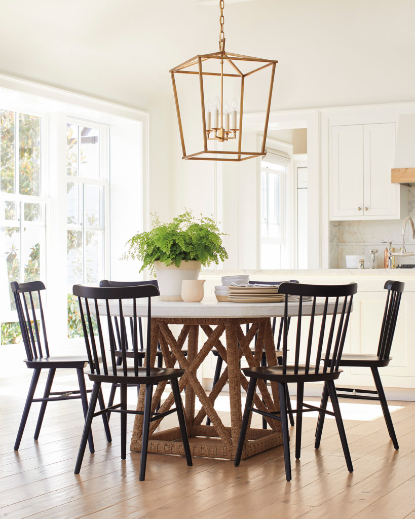 Gold pendant light with candlestick lightbulbs over a round white table.