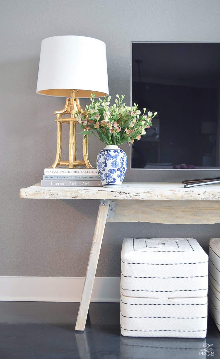 console table with vase of flowers and a lamp sitting on stacked books