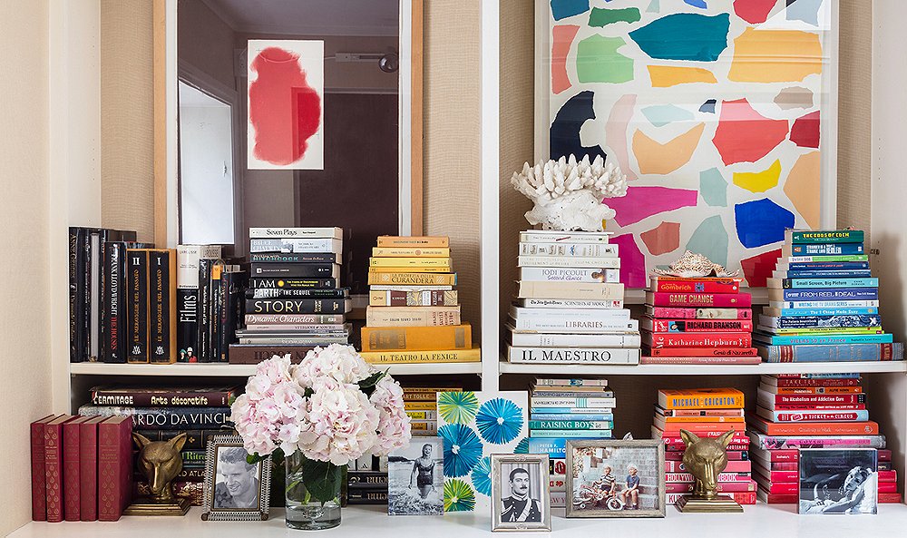 shelving decor with flowers, trinkets and books stacked according to color