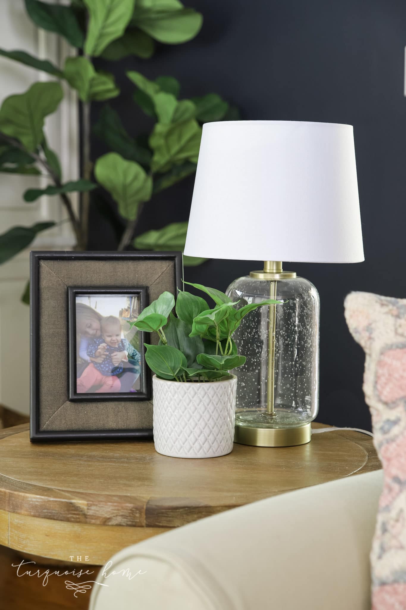 end table with lamp, frame and greenery