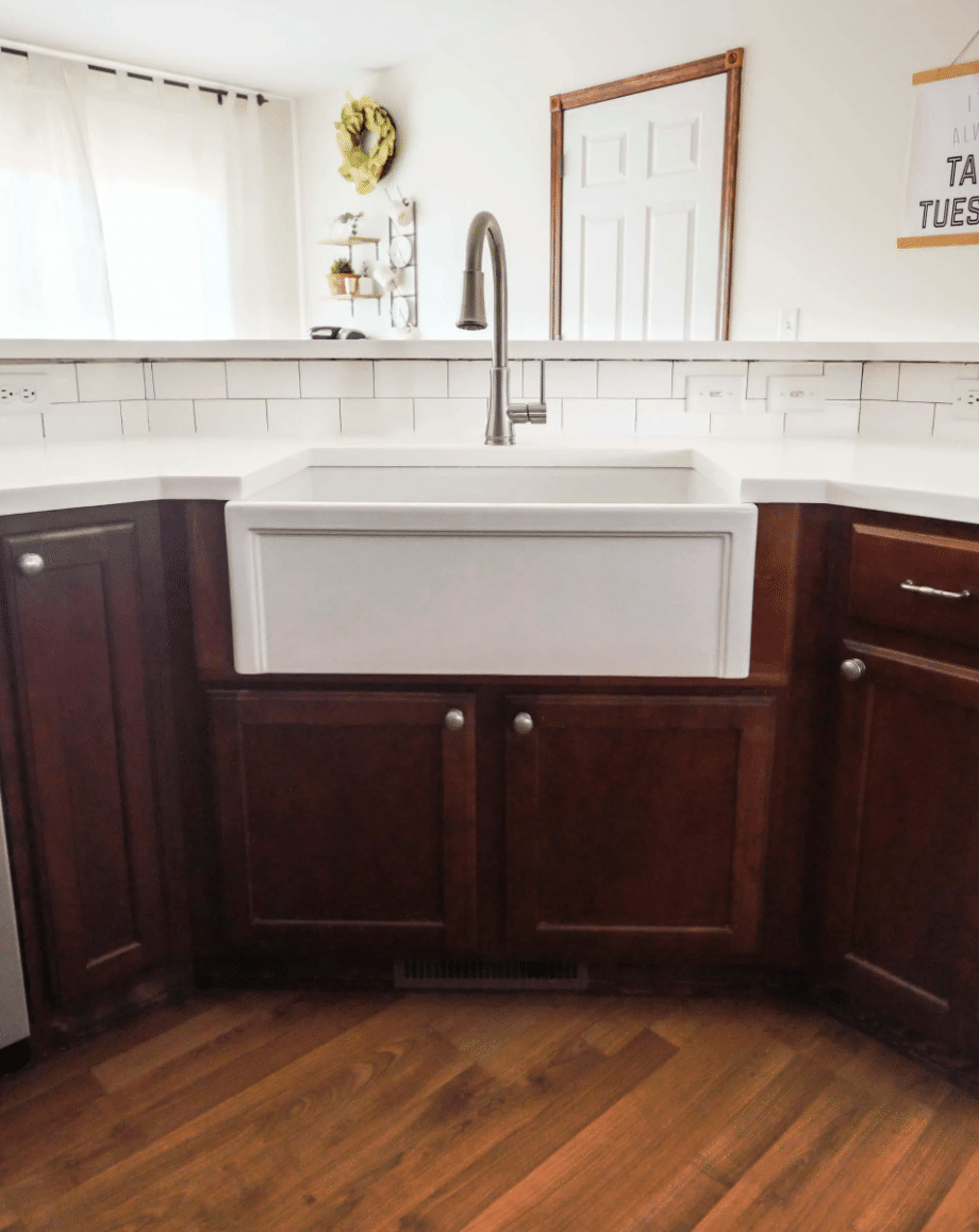 white farmhouse sink with dark wood cabinets