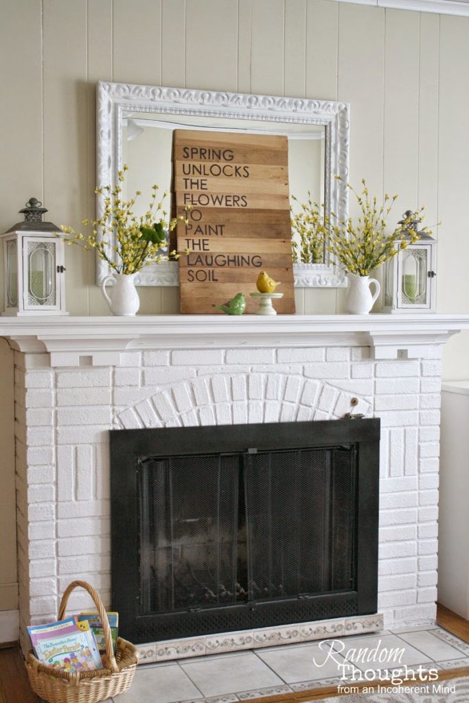 forsythia blooms on a white fireplace mantel with a sign and bird figurines