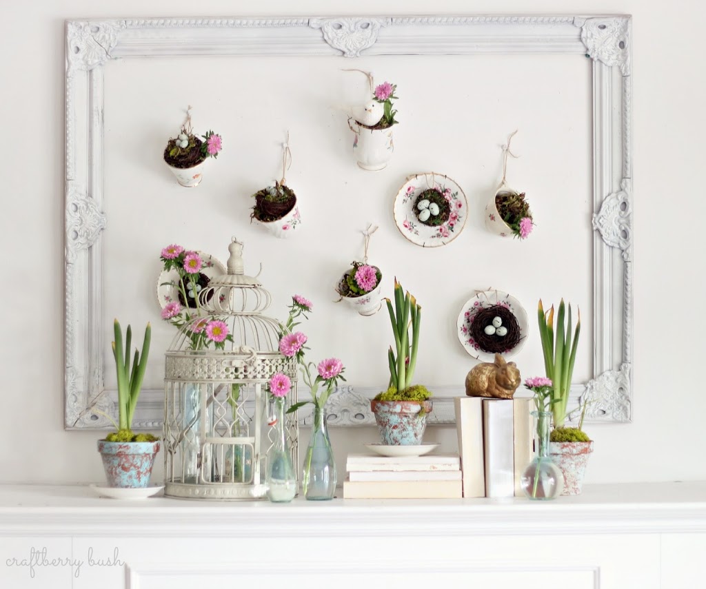teacups hanging on the wall over fireplace mantel holding spring blooms