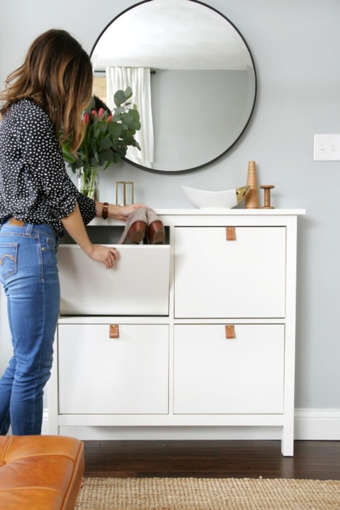 IKEA shoe cabinet dressed up with leather pulls and a large round mirror.