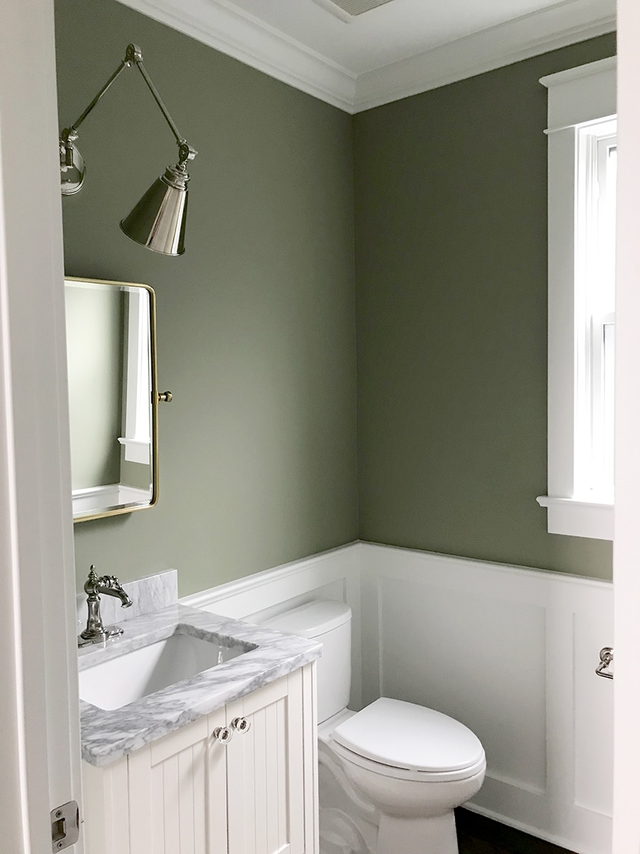 Powder room upper walls painted in Lichen by Farrow & Ball, paired with bright white wainscoting.