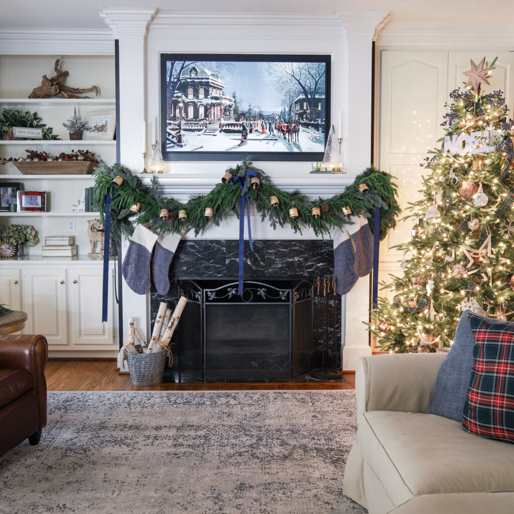 Mantel draped in holiday greenery garland with Christmas bell decoration added on