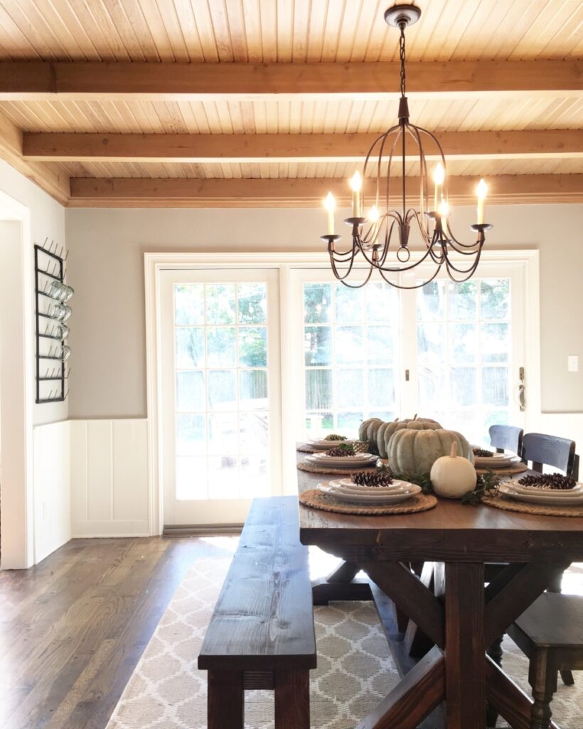 Dining room with warm wood ceiling, off-white trim and wainscoting and walls painted in Mindful Gray.