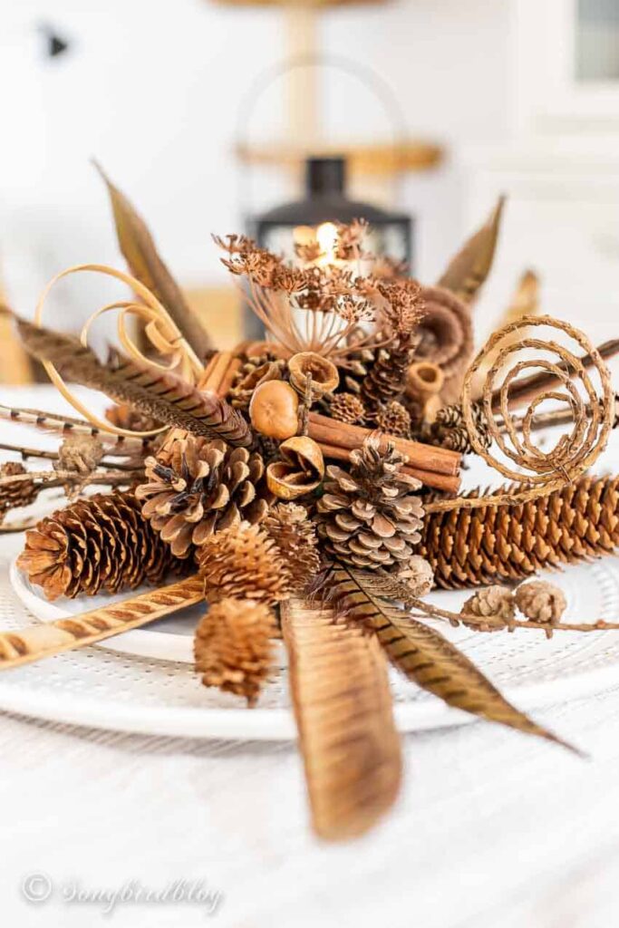 pinecones, cinnamon sticks, feathers, and florals in a fall centerpiece 