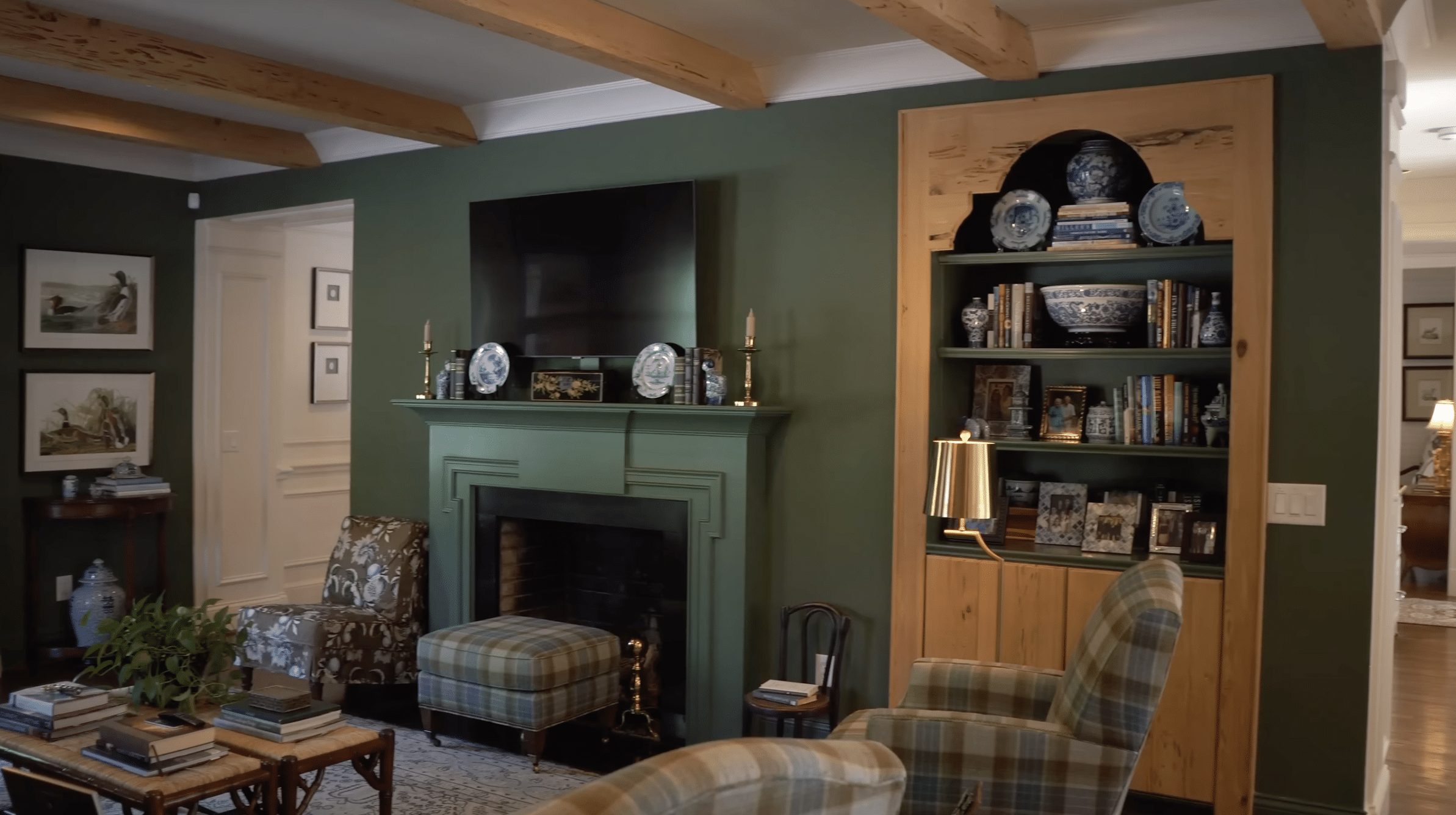 Eric Ross' Green Family Room with a mantel and TV above it and built-in wooden bookshelves. 