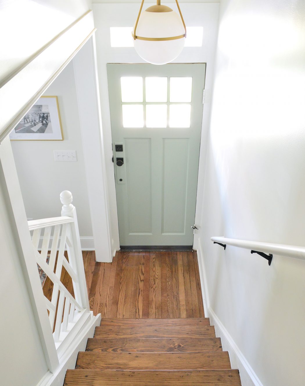 Light-filled entry way with wooden floor and front door painted Oyster Bay