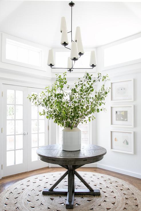 round gray wood trestle table with round crochet rug