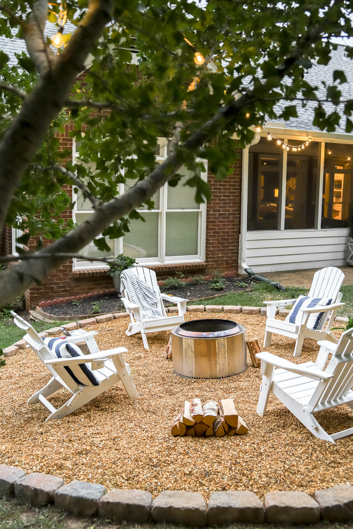 Fire pit area with white adirondack chairs, pea gravel and Yukon Solo Stove.