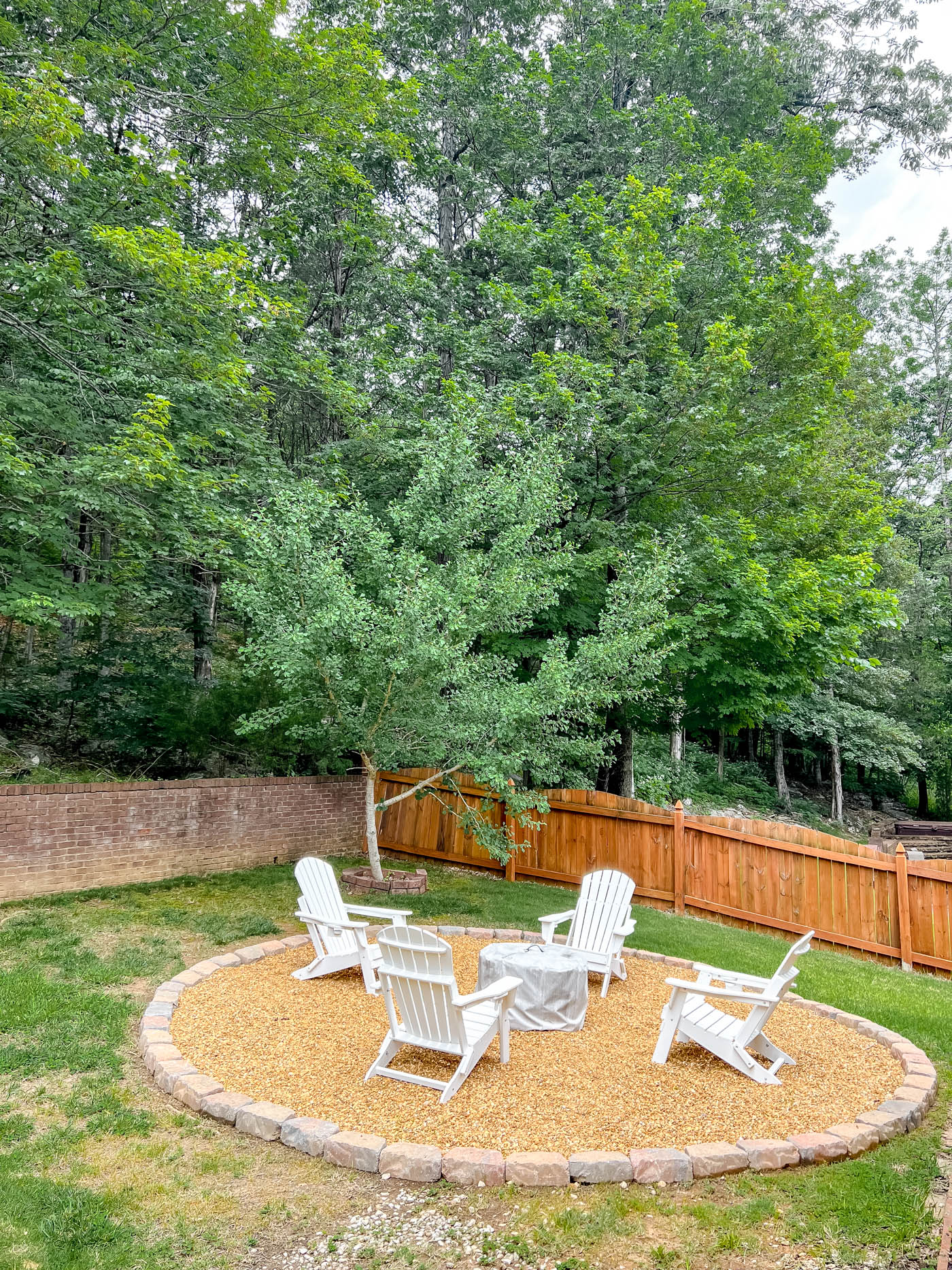 pea gravel fire pit in the backyard with white adirondack chairs and solo stove fire pit.