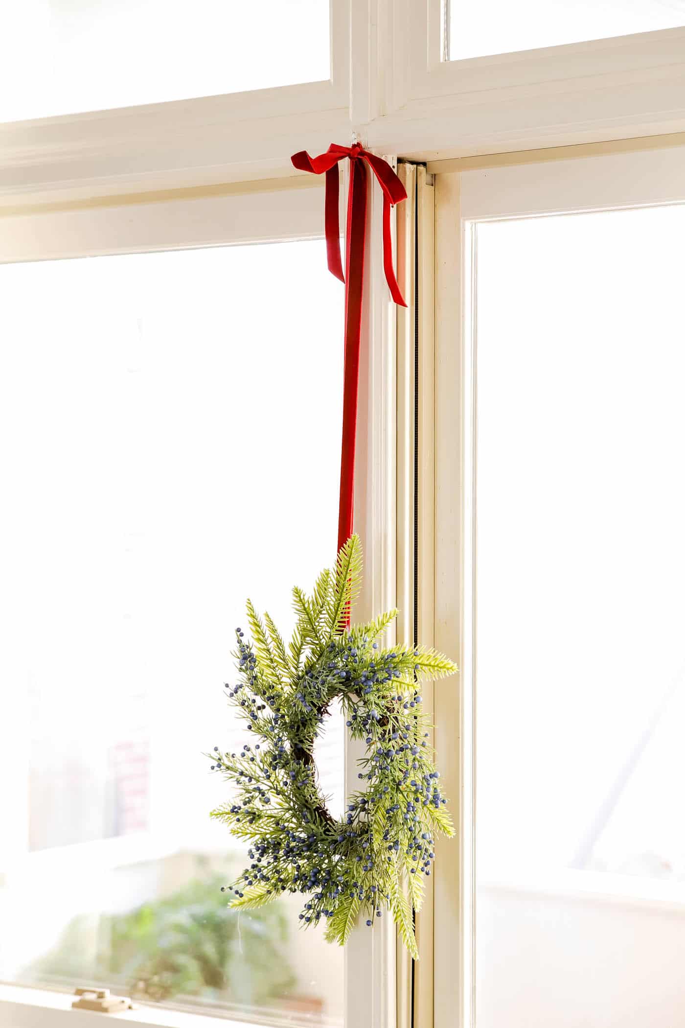 Pine and Berry Wreaths in Window with red ribbon