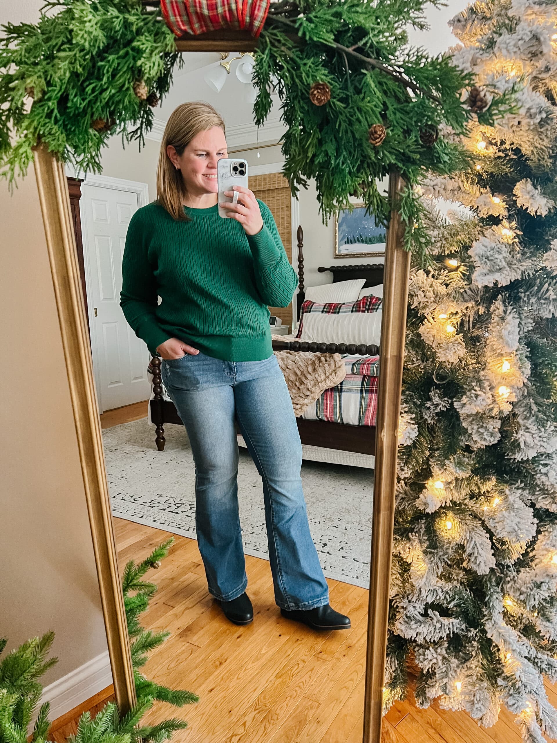 green sweater, jeans, boots outfit in a Christmas bedroom