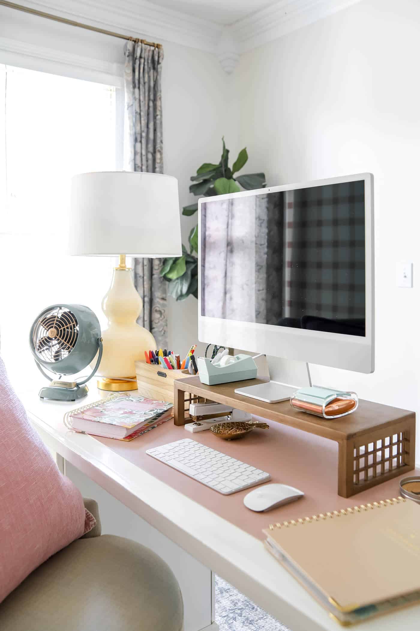 organized desk space with mc computer and desk riser, fan and lamp.